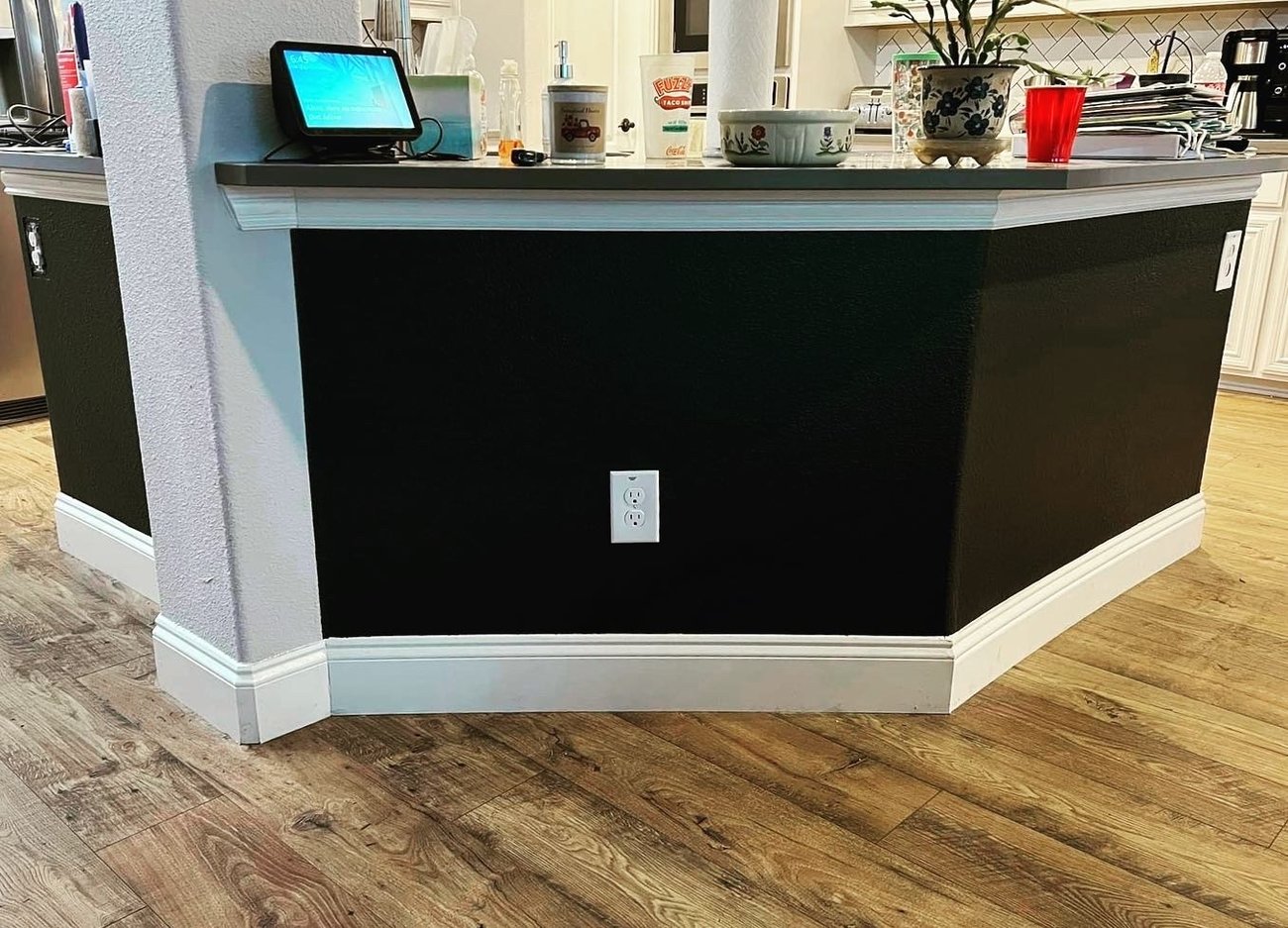 Black accent wall and white trim painted around a kitchen peninsula