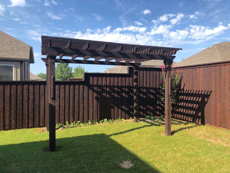 Stained wood pergola and fence in a Frisco backyard