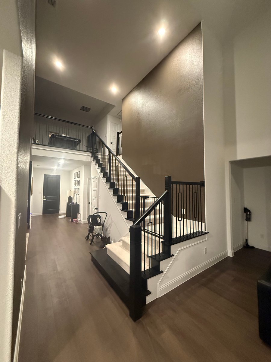 Two story stairwell with a dark accent wall and black railings